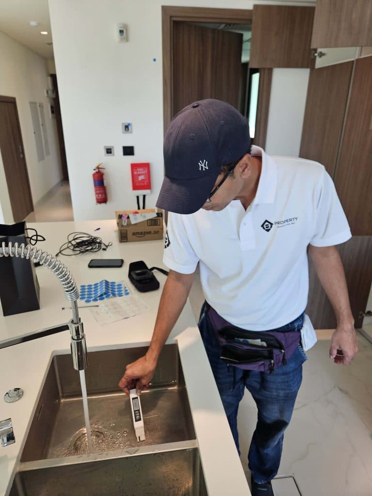 Engineer testing a kitchen sink and its drainage during an apartment inspection