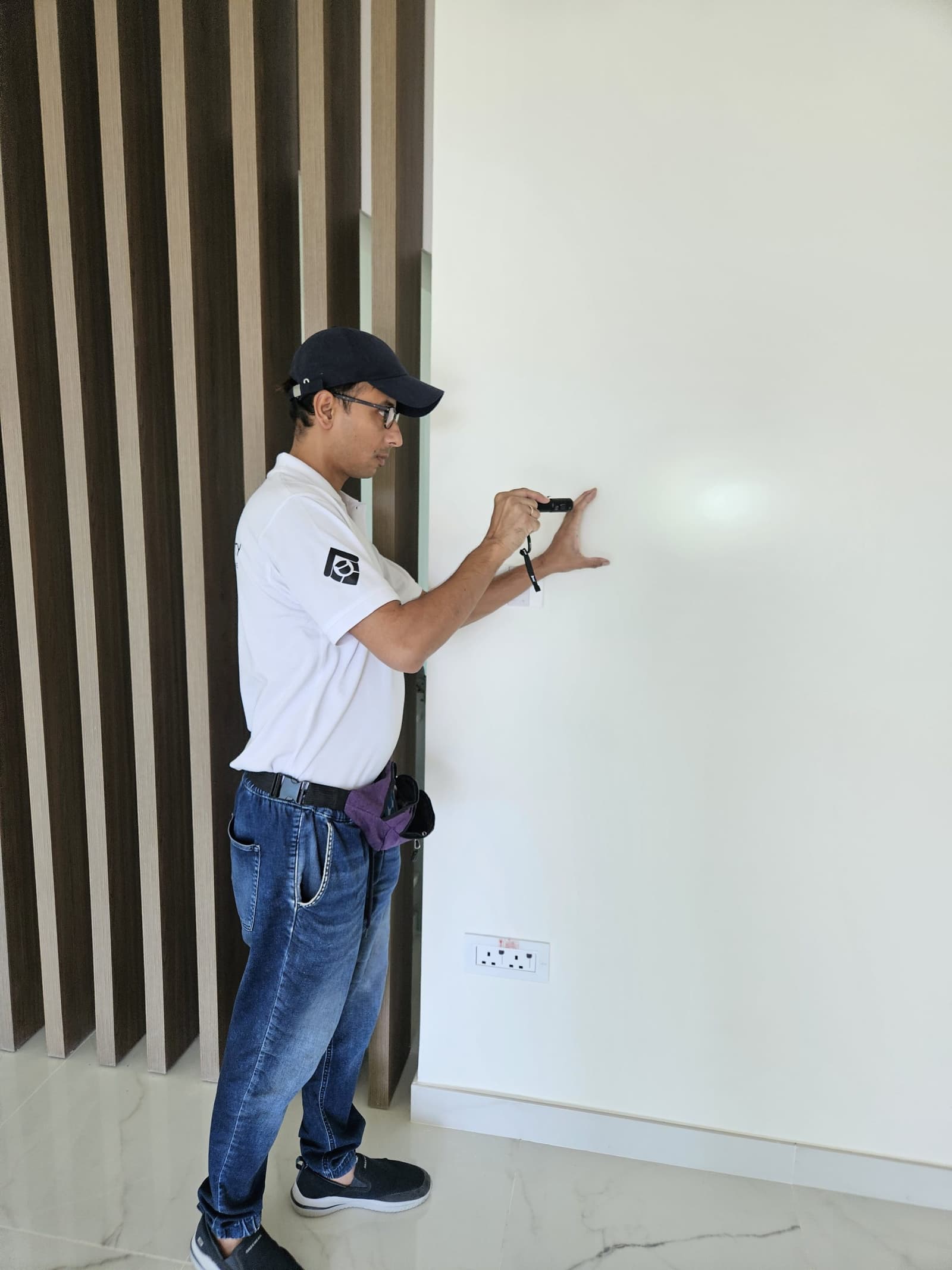 Engineer checking a freshly painted wall with a torch during a snagging inspection