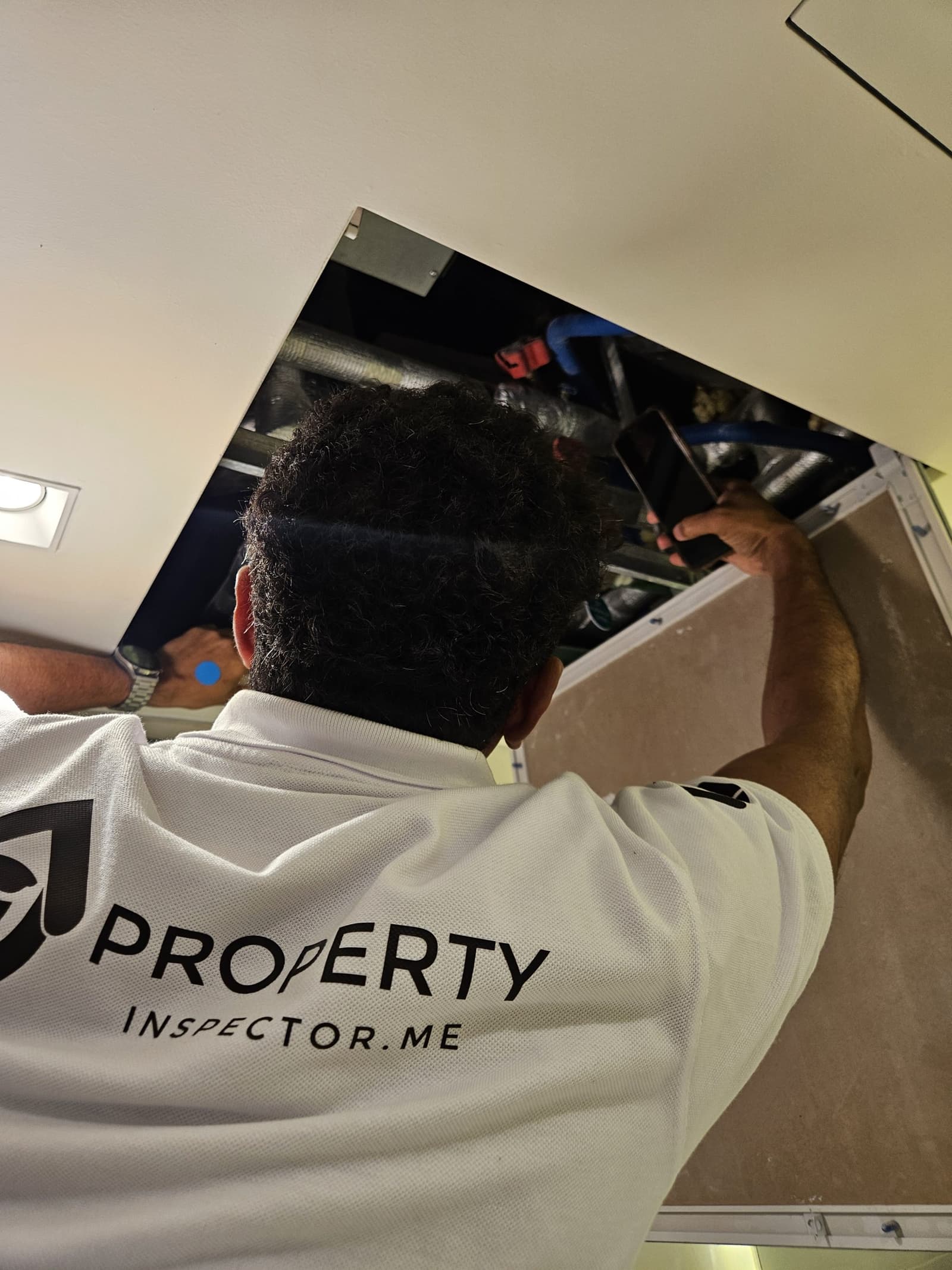 Engineer inspecting an AC unit through a ceiling access panel